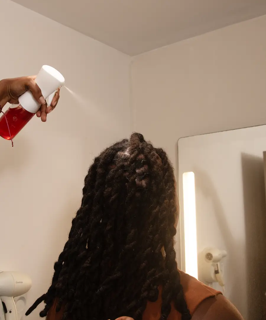 Infusion Tonique Tea Rinse appliquée sur des cheveux foncés et texturés, vus de dos